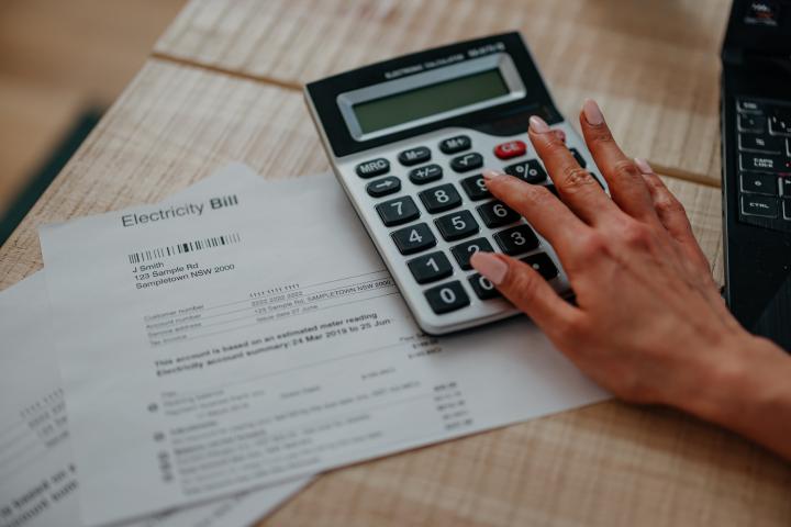 A close-up of a young hand using a calculator, while sorting their bills.